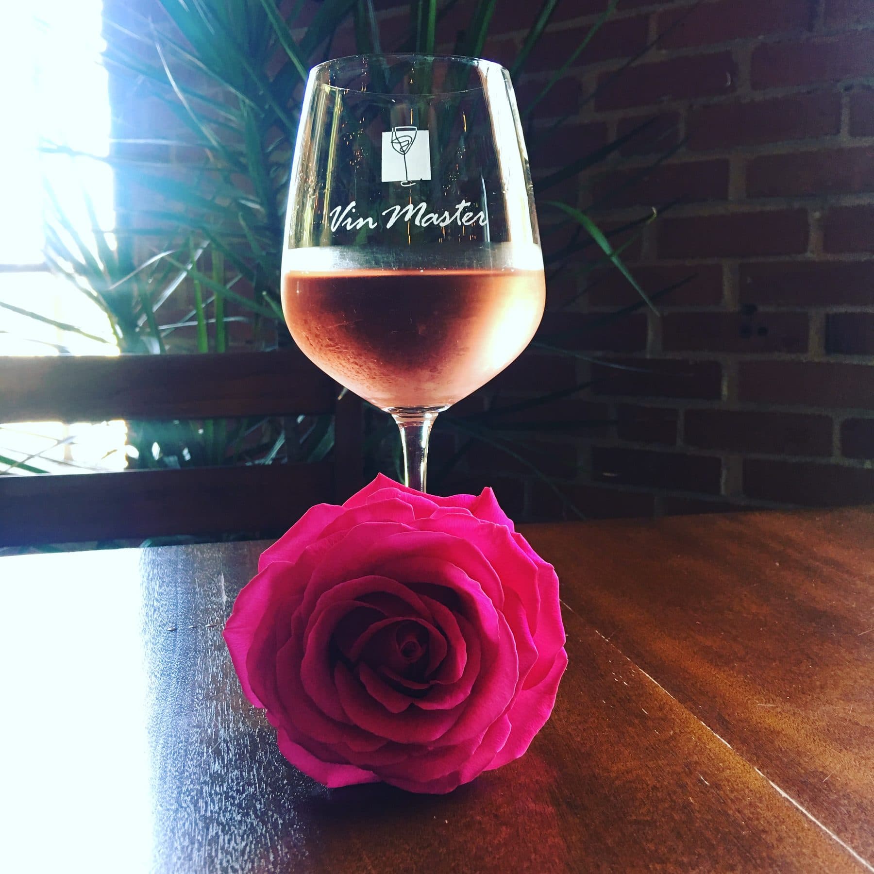Rosé in a Vin Master glass beside a pink rose